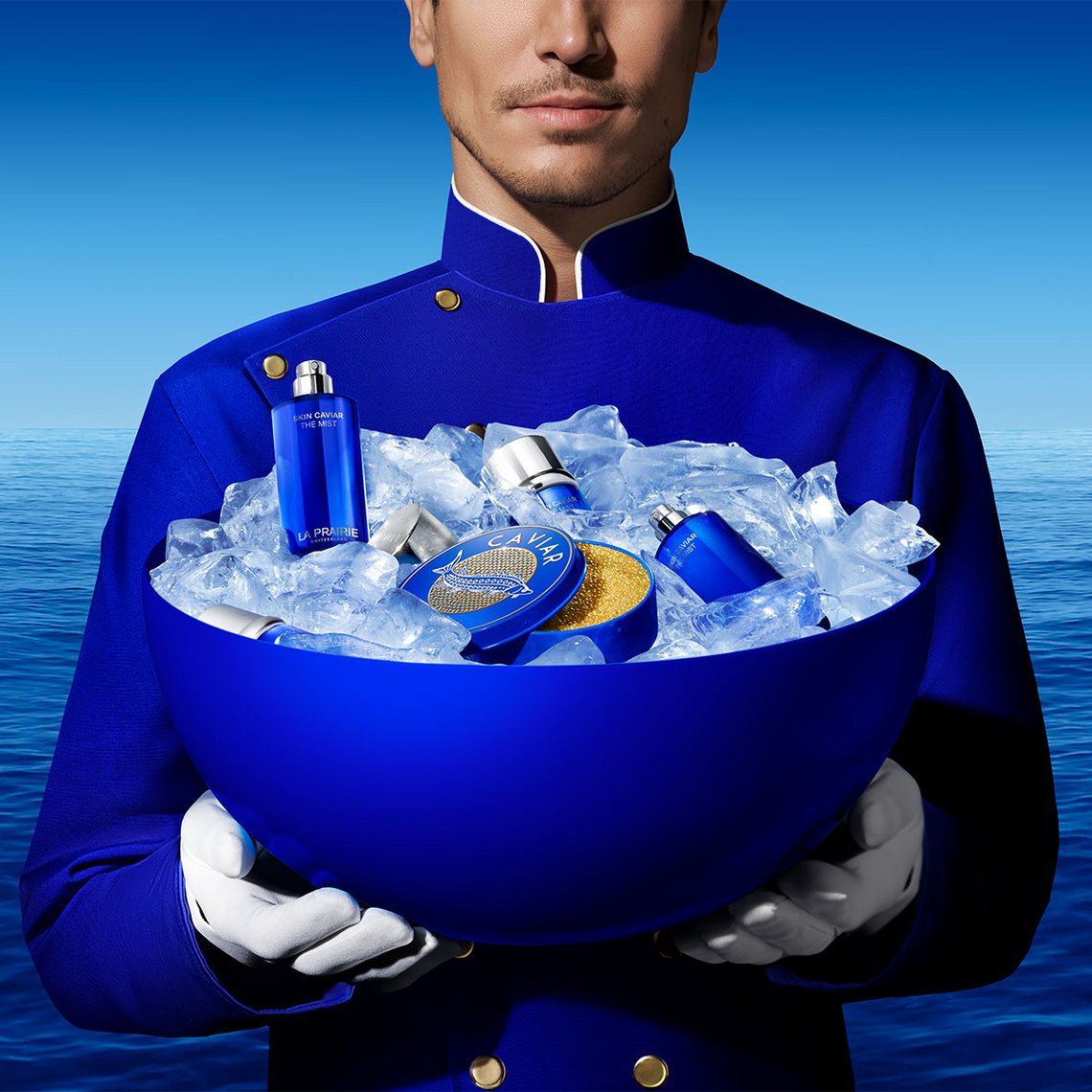 Mann in blauer Uniform trägt einen Eiskübel vor sich, darin liegt ein Flakon von SKIN CAVIAR THE MIST von La Prairie