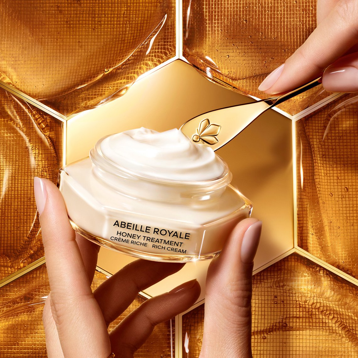 Nahaufnahme des offenen Tiegel der Abeille Royale Honey Treatment Rich Cream von GUERLAIN, im Hintergrund Honigwaben